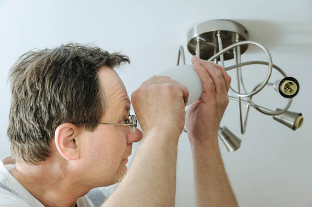 istock Electrician is installing a LED light bulb. 872208584