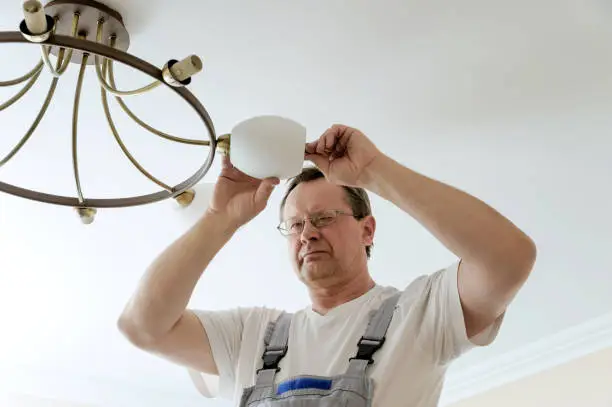 Electrician is attaching a plafond to a seiling lamp.
