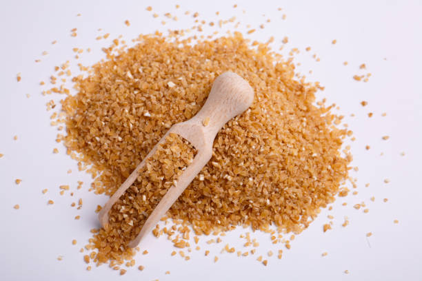 Mamaliga in a wooden shovel on white background, top view. A pile of cereals, hominy, on it lies a wooden scoop on a white background, top view. mamaliga stock pictures, royalty-free photos & images