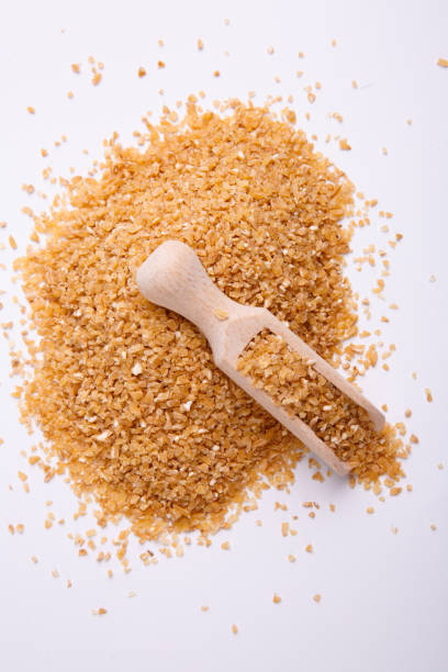 Mamaliga in a wooden shovel on white background, top view. A pile of cereals, hominy, on it lies a wooden scoop on a white background, top view. mamaliga stock pictures, royalty-free photos & images