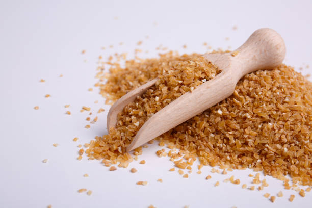 Mamaliga in a wooden shovel on white background A pile of cereals, hominy, on it lies a wooden scoop on a white background mamaliga stock pictures, royalty-free photos & images