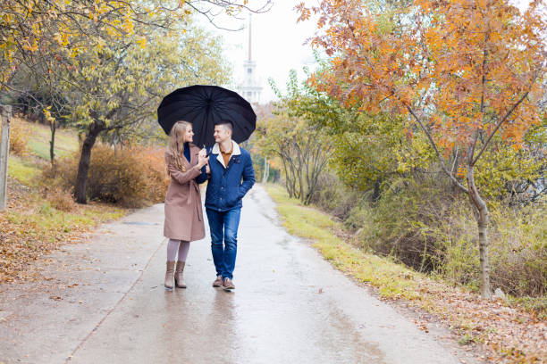 istock a guy with a girl go under umbrella rain 872218406