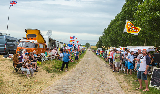 Quievy,France - July 07, 2015:Spectators and caravans are on the cobblestone road during the stage 4 of Le Tour de France 2015 in Quievy, France, on 07 July,2015.