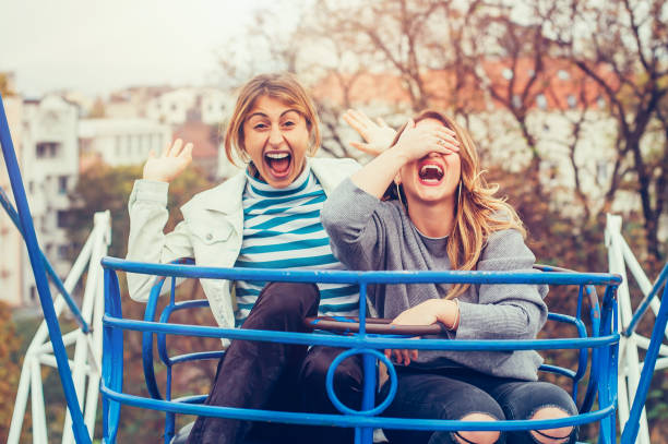 istock Two cheerful girls having fun on merry go round 872228380