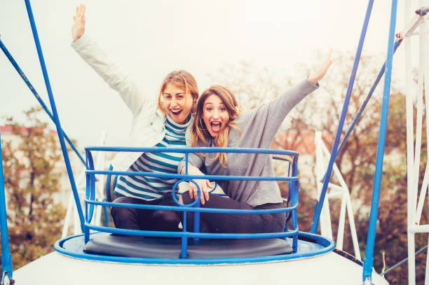istock Two cheerful girls having fun on merry go round 872228548