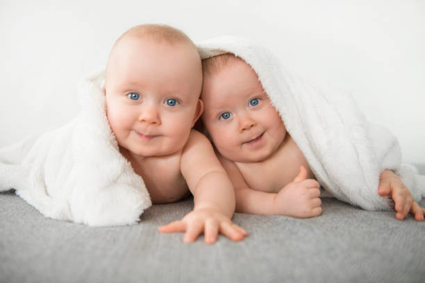 идентичные близнецы под одеялом - babies and children close up horizontal looking at camera стоковые фото и изображения