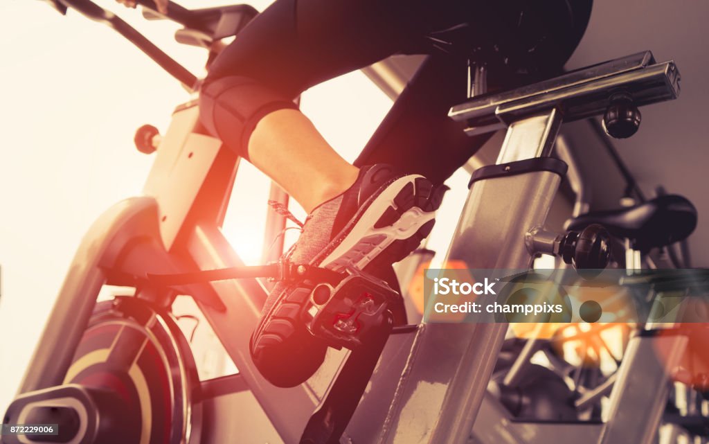Exercise bike cardio workout at fitness gym of woman taking weight loss with machine aerobic for slim and firm healthy in the morning. Exercise Bike Stock Photo