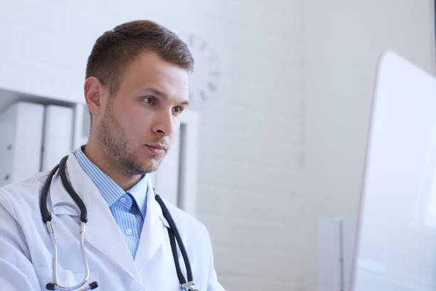 istock Young male doctor using computer on desk in clinic. 872249268