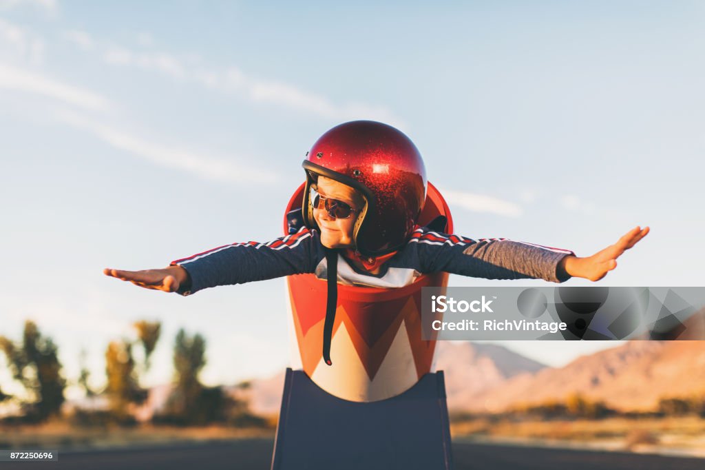Young Stunt Boy and Human Cannon Ball A young boy dressed in helmet and flight goggles sits ready for flight in a homemade cannon. His arms are outstretched and ready for take off as he is excited to explore new heights. Image taken on a rural road in Utah, USA. Child Stock Photo