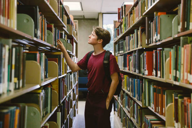 istock Student in library looking for books on bookshelf 872254076