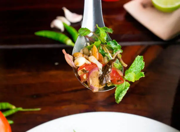 Burmese Tea Leaf Salad on spoon and on dark wooden