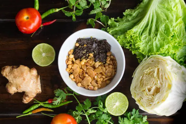 Burmese Tea Leaf Salad with vegetables on dark wooden