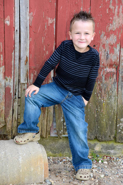 istock smiling Caucasian boy by red barn 872263630