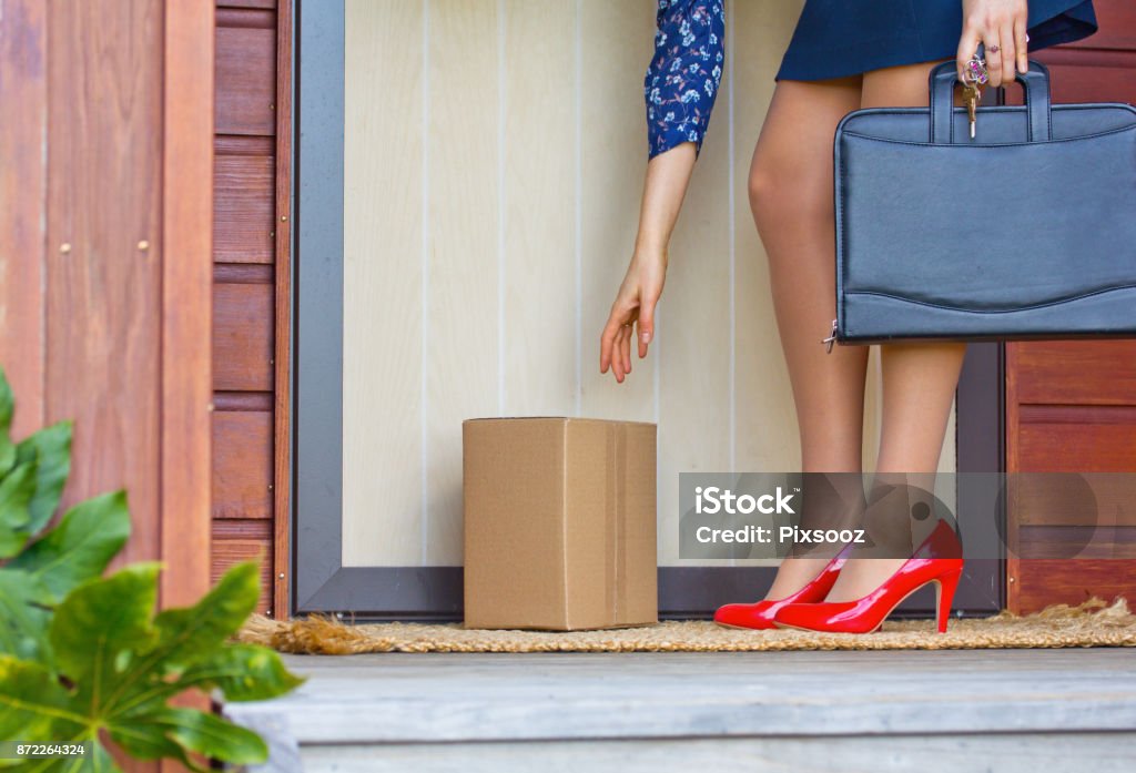 Mujer de rojo tacones recoge el paquete en la puerta de casa - Foto de stock de Servicio de entrega libre de derechos