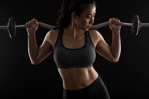 istock Beautiful girl exercising squatting with barbell 872275260