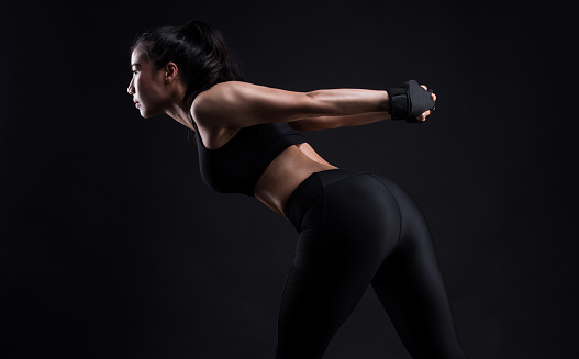 Fitness woman doing stretching workout on black background,Warming up before training.