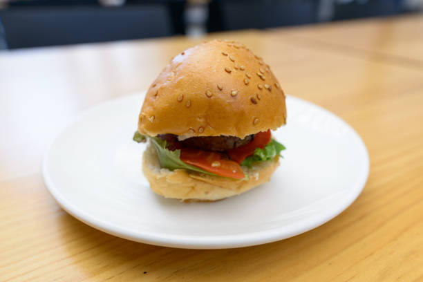 istock Small bit-sized hamburger served in white plate on wooden table 872278108