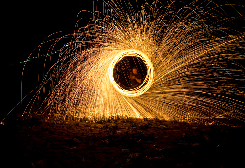 Man spinning the burning steel wool at night