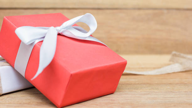 istock Red gift box on wood table background vintage style with copy space. Red and white gift box with white and brown ribbon for decoration. Christmas, New year, Valentine or Birthday concept. Still life. 872297946