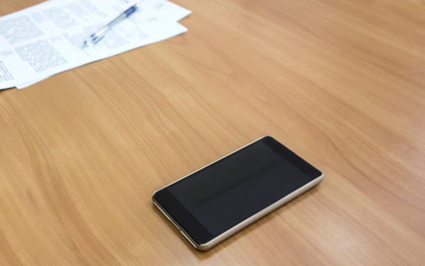 istock Mobile phone, paper and pen on a wooden table 872297960