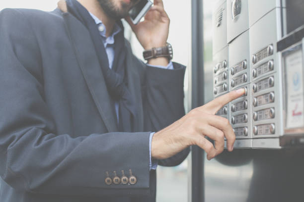 istock Businessman rings at a business building and using mobile phone. Focus is on hand. 872301182