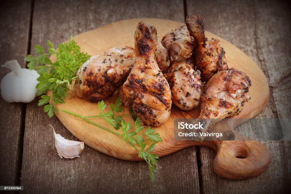 Grilled chicken legs on cutting board.Rustic dinner background Grilled chicken legs on cutting board.Rustic dinner background. Chicken - Bird Stock Photo