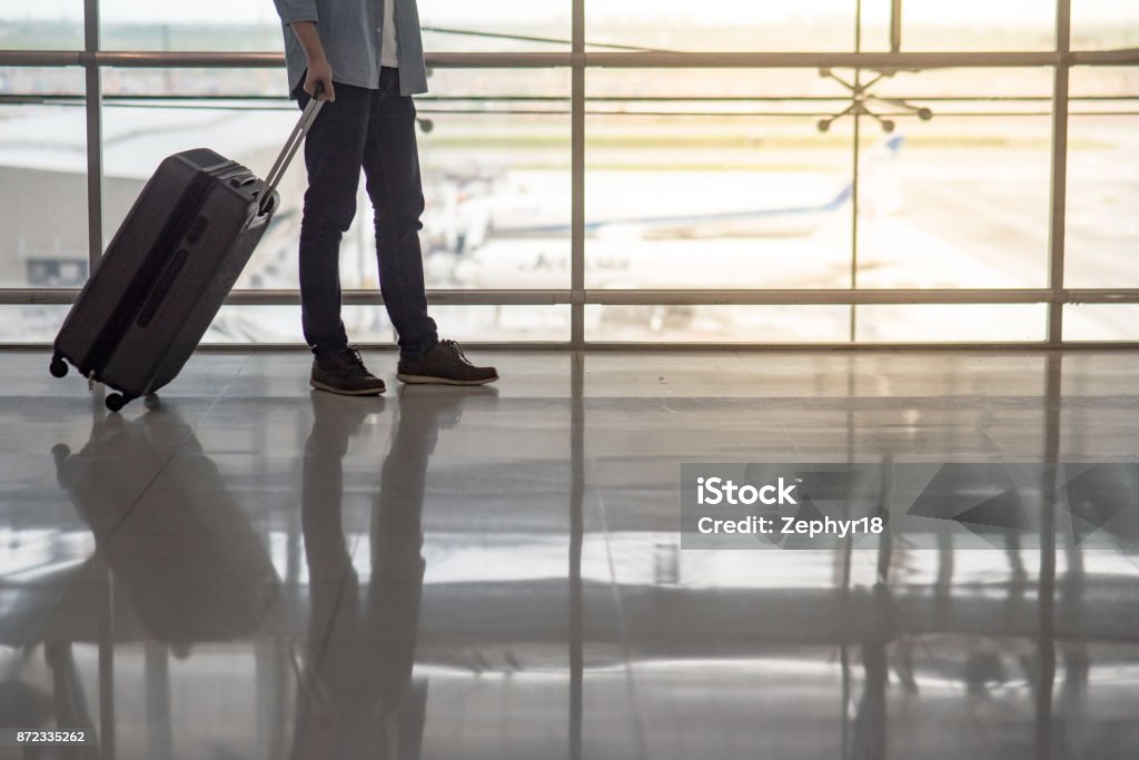 Reflexión de medio cuerpo hombre a pie en el aeropuerto con equipaje maleta - Foto de stock de Hombres libre de derechos