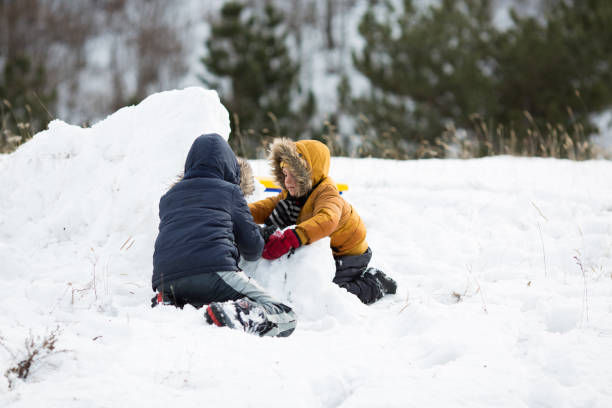 istock Two brothers having winter fun sliding on show 872339030