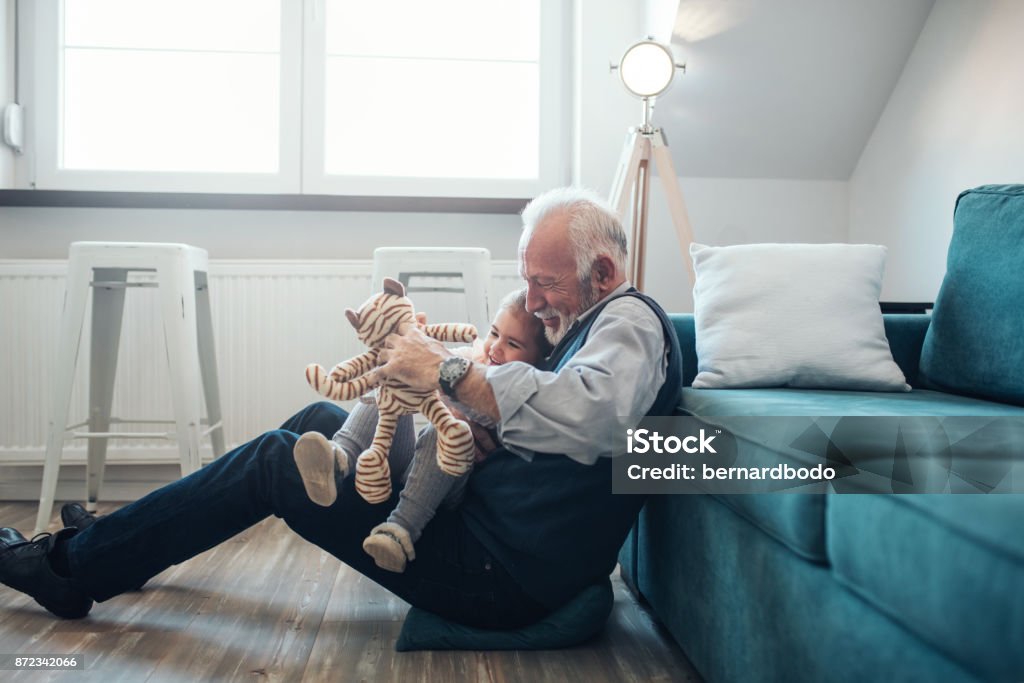 Together is the only place we want to be Mature man playing with granddaughter at home. Grandfather Stock Photo
