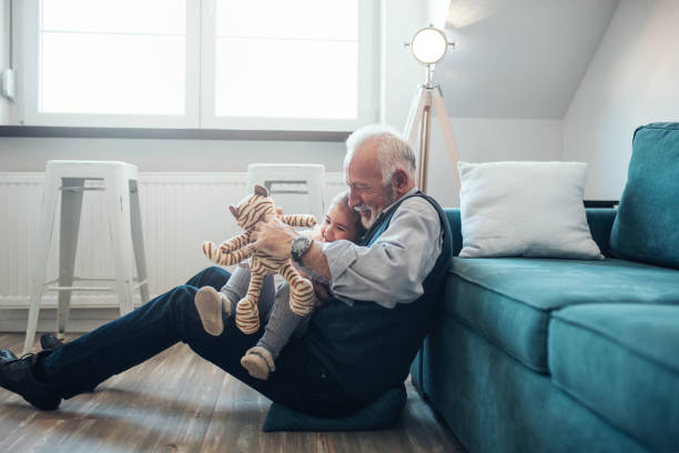 Together is the only place we want to be Mature man playing with granddaughter at home. granddaughter stock pictures, royalty-free photos & images