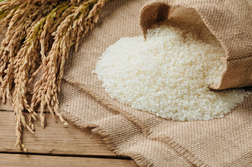 Granos de arroz crudo y plantas de arroz seco en mesa de madera photo
