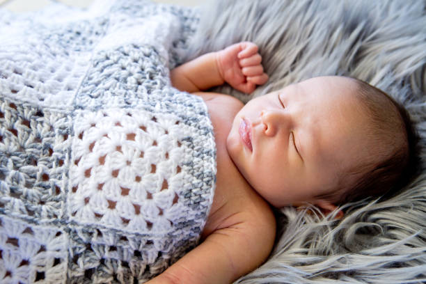 istock New Baby Boy sleeping covered by grey and white crotcheted blanket 872343272