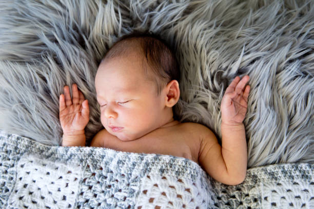 istock New Baby Boy sleeping covered by grey and white crotcheted blanket 872346154