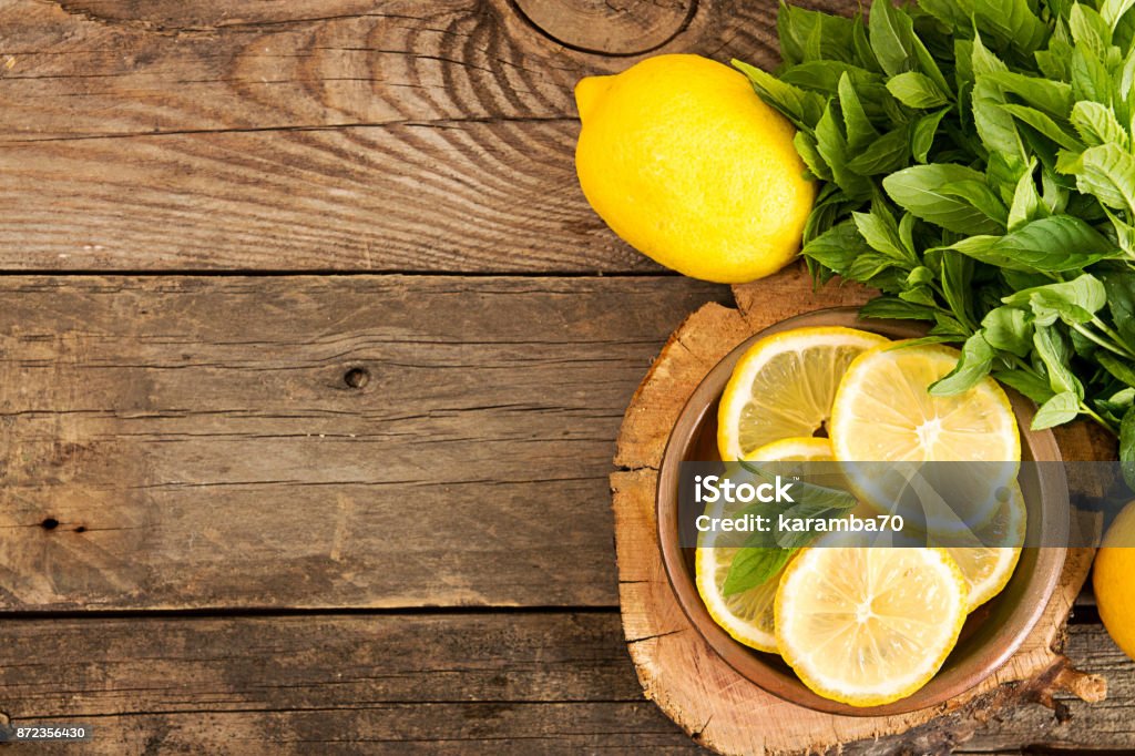 Bundle of mint and slices of lemon on old wooden background. Copy space. Top view. Rustic style Lemon - Fruit Stock Photo