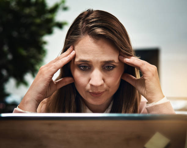 istock Tired looking blonde office worker stares at computer monitor 872356604