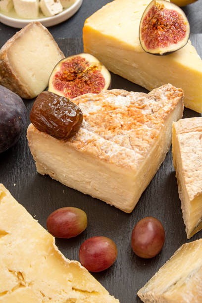 istock Food composition with blocks of moldy cheese, grape, figs on black background. 872356774