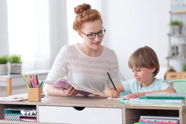 Private tutor helping young student Private female tutor helping young student with homework at desk in bright child's room private teacher stock pictures, royalty-free photos & images