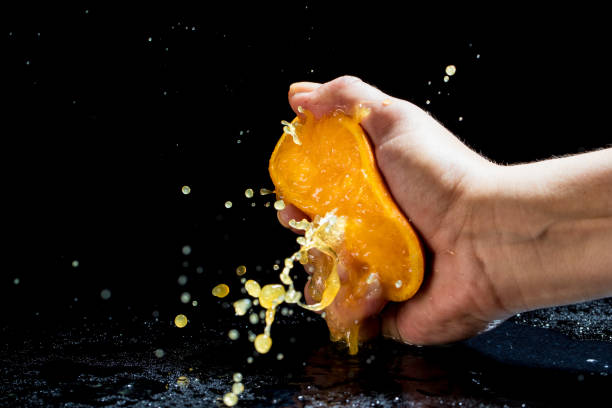 Squeezing orange Woman's hand squeezing orange crushed stock pictures, royalty-free photos & images