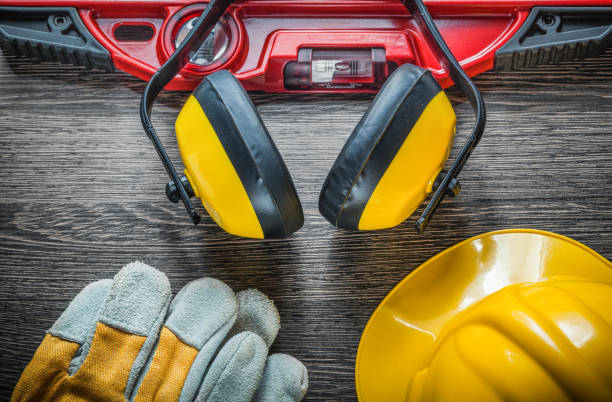 istock Construction level safety gloves hard hat earmuffs on wooden boa 872358220