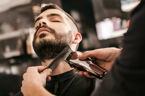 Hombre de recibir su barba cortan con máquina de afeitar eléctrica photo