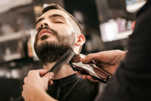 Man getting his beard trimmed with electric razor stock photo