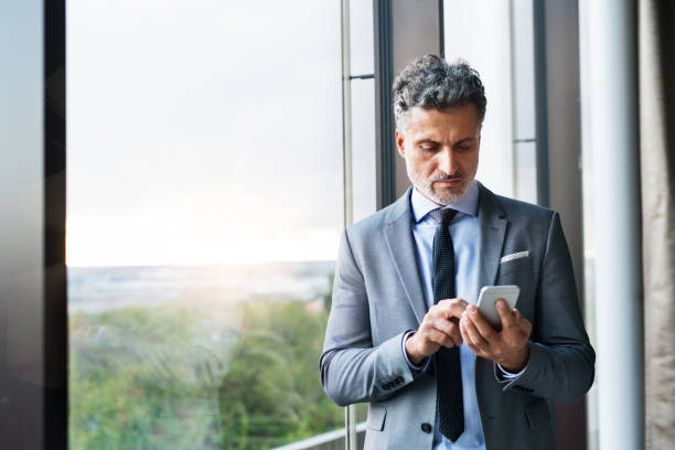 istock Mature businessman with smartphone in a hotel. 872365684