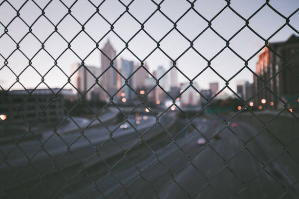 Grunge city skyline through the wire mesh fence. Abstract blurred cityscape background