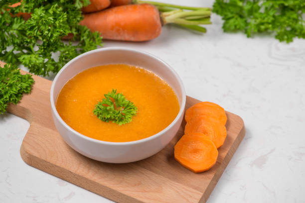 istock Carrot soup with cream and parsley on white stone background. Top view. Copy space 872382228