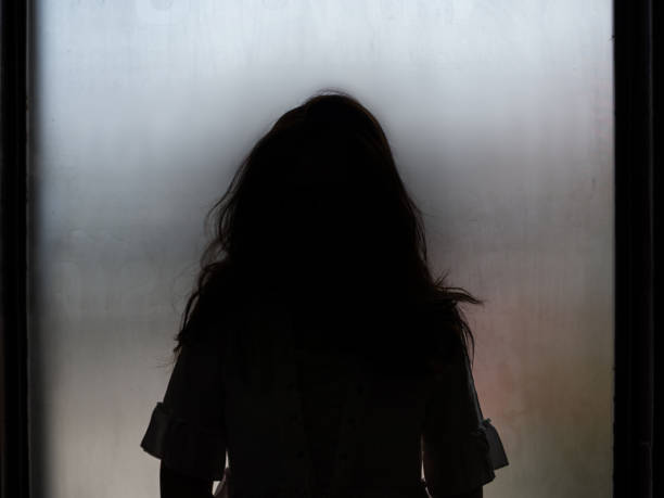 istock Ghost girl silhouette standing in front of window 872386372