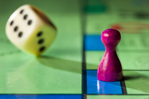 Board game with pawn and rolling dice Close up of a board game with pawn and rolling dice board game piece stock pictures, royalty-free photos & images