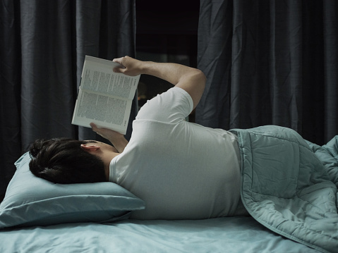 Man reading book in the bed at night