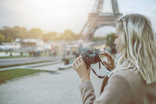 istock Young woman in Paris with camera in hands, checking pictures 872393292