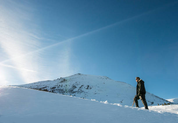 istock climber with an ice ax walking in the snowy mountains 872397860