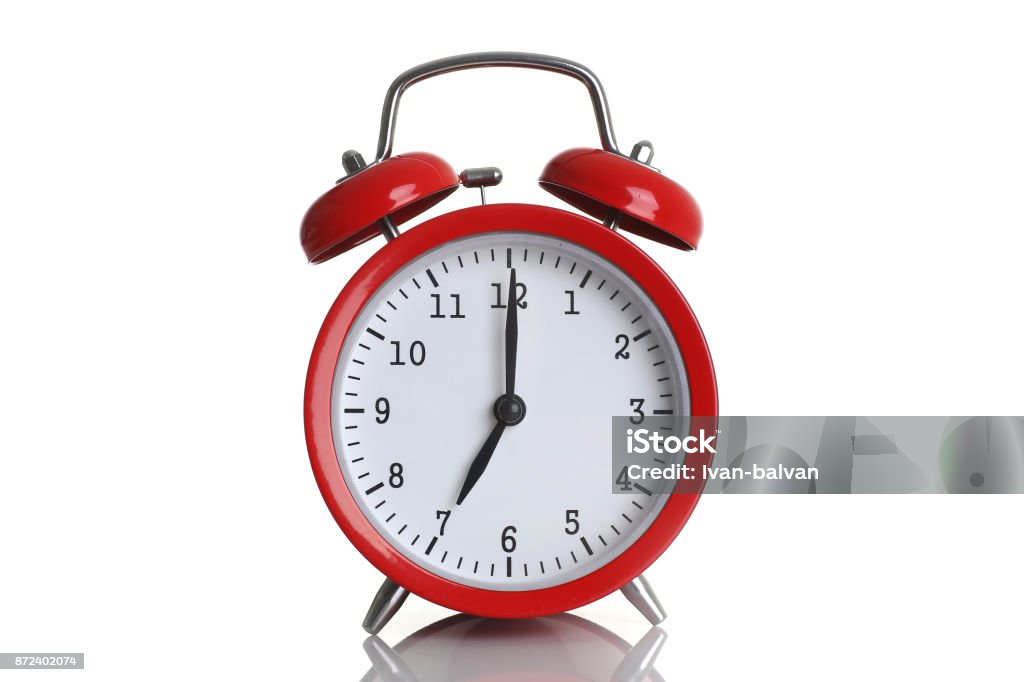 Red alarm clock isolated on white Red alarm clock isolated on white background shows seven o clock in the morning time to get up to wake up and have breakfast morning or evening run to go to work 7 am pm. Alarm Clock Stock Photo